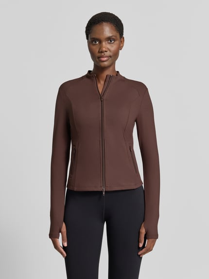 Frauenmodel trägt Jacke mit Zweiwege-Reißverschluss Modell 'Sense' von aim'n, dunkelbrauner Material-Mix mit Stretch, schlichte Struktur, Ganzkörperansicht von vorne.