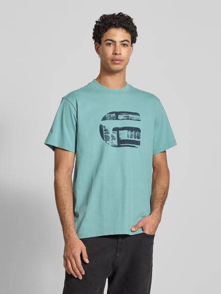 Männermodel trägt Regular Fit T-Shirt mit Logo-Print Modell 'icon' von G-Star Raw in Hellblau, reine Baumwolle, Ganzkörperansicht von vorne.
