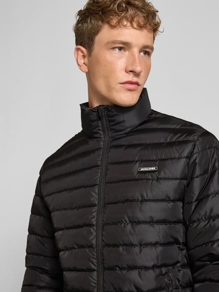 Männermodel trägt schwarze Jacke mit Label-Patch Modell 'ELVIS' von JACK & JONES, Stehkragen, Reißverschluss, Nahaufnahme Oberkörper.