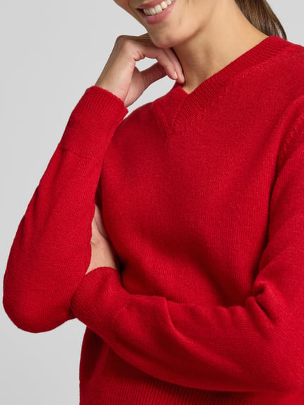 Frauenmodel trägt Strickpullover mit V-Ausschnitt Modell 'LIMONI' von MANGO in Rot mit elastischen Abschlüssen, Nahaufnahme Oberkörper. Damen Strickpullover, Regular Fit, Rückenlänge 52 cm, Ärmellänge 58 cm.