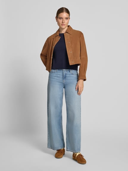 Frauenmodel trägt Regular Fit Strickpullover aus reinem Kaschmir von Christian Berg Woman in Dunkelblau, Rundhalsausschnitt, Ziernaht, Langarm, kombiniert mit weiter Jeans und brauner Jacke, Ganzkörperansicht von vorne.