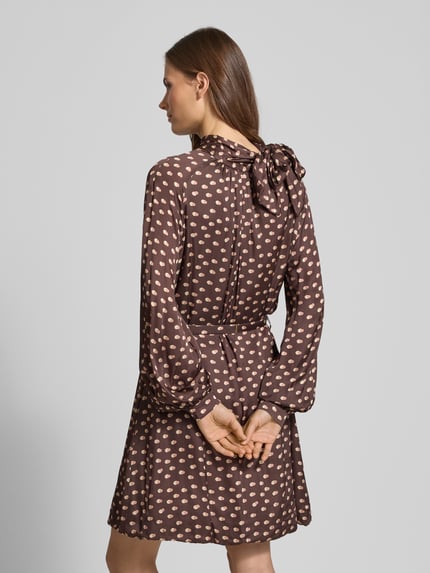 Vrouwenmodel draagt cocktailjurk met opstaande kraag van Rinascimento, bruin met beige print, taille ceintuur, rugaanzicht geheel.