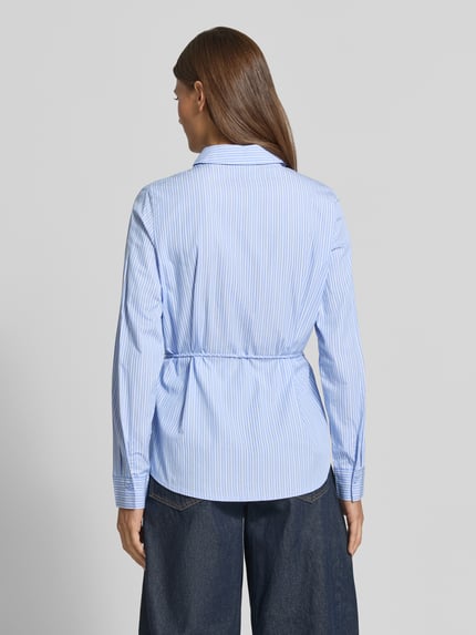 Frauenmodel trägt Regular Fit Hemdbluse aus reiner Baumwolle Modell 'ELINA' von VERO MODA, hellblau mit feinen weißen Streifen, Ganzkörperansicht Rückansicht. Damen Hemdbluse von VERO MODA.