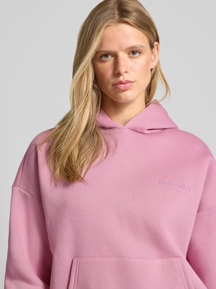 Frauenmodel trägt Relaxed Fit Hoodie aus Baumwoll-Mix mit Label-Detail von REVIEW, Känguru-Tasche, elastische Abschlüsse, Rosa, Nahaufnahme Oberkörper