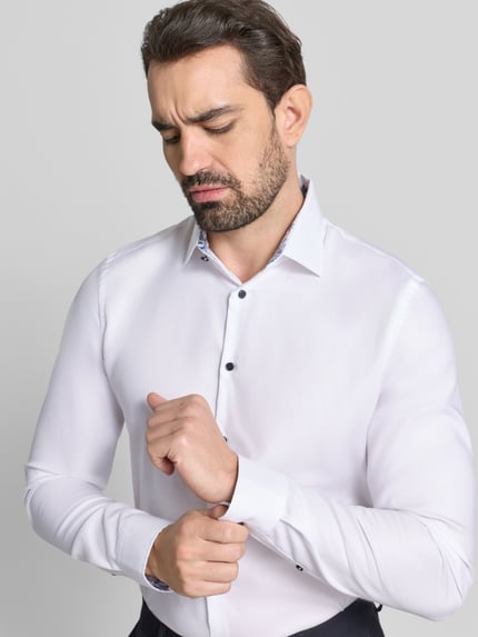 Männermodel trägt Slim Fit Businesshemd mit extra langem Arm von Jake*s in Weiß, glatte Baumwolle, Kentkragen, Nahaufnahme Oberkörper.