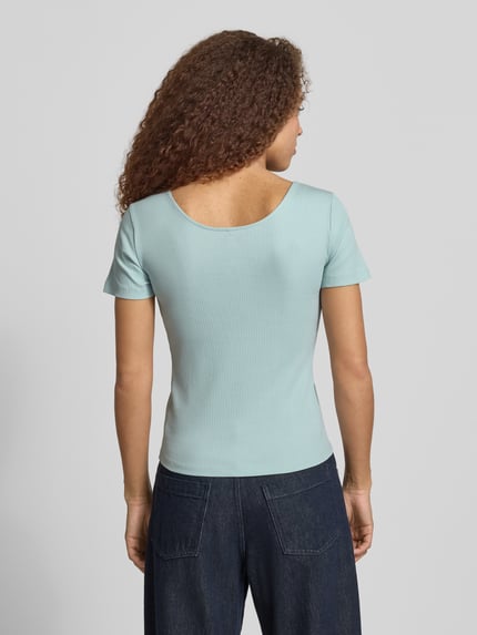 Vrouwenmodel draagt effen kleuren slim fit T-shirt met knoopdetail, u-hals en riblook van katoenmix, model 'SIMPLE' van Only, rugdecolleté. Ganzkörperansicht Rückansicht.