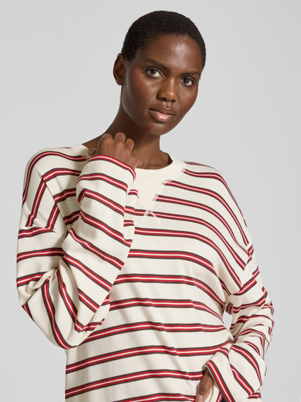 Frauenmodel trägt Relaxed Fit Longsleeve aus Baumwoll-Mix mit Streifenmuster von Closed, cremefarben mit roten und schwarzen Streifen, Nahaufnahme Oberkörper. Rückenlänge bei Größe S: 59 cm, Rundhalsausschnitt.