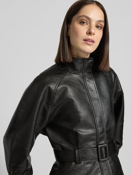 Frauenmodel trägt Jacke in Leder-Optik mit Gürtel Modell 'Jaclyn' von Neo Noir, schwarze Farbe, Struktur sichtbar, Nahaufnahme Oberkörper. Damen Jacke, Relaxed Fit, Stehkragen, Produktdetails: Rückenlänge 57 cm, Schulterbreite 41 cm, Brustweite 51 cm, Ärmellänge 62 cm.