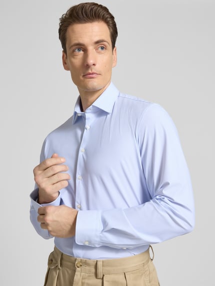 Männermodel trägt Slim Fit Business-Hemd mit Kentkragen von Jake*s in Hellblau, Elastischer-Material-Mix, Langärmelig, Knopfleiste, Nahaufnahme Oberkörper.