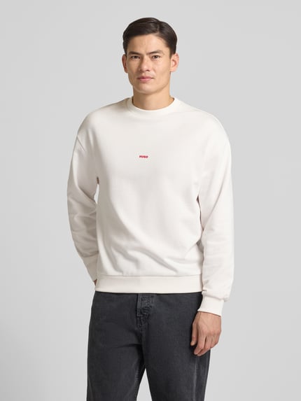 Männermodel draagt Regular Fit sweatshirt uit puur katoen model 'DUBRAXO' van HUGO, look: effen, labelstitching, motiefprint, ronde hals, lange mouw, mouwboord en rompzoom geribd, sweat materiaalverwerking, kleur licht, voorkant, nahaufnahme bovenlichaam.