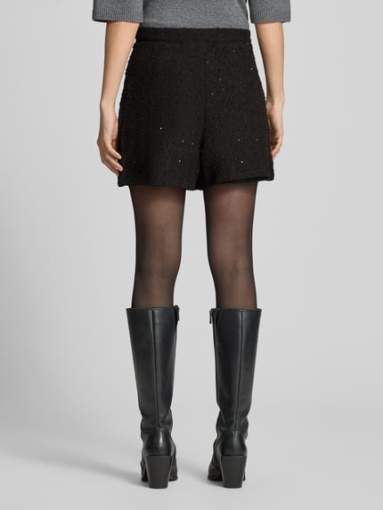 Frauenmodel trägt Regular Fit Shorts in Wickel-Optik Modell 'NINKY' von ICHI, Strukturmuster, Schwarz, Material-Mix mit Stretch, Ganzkörperansicht Rückansicht.