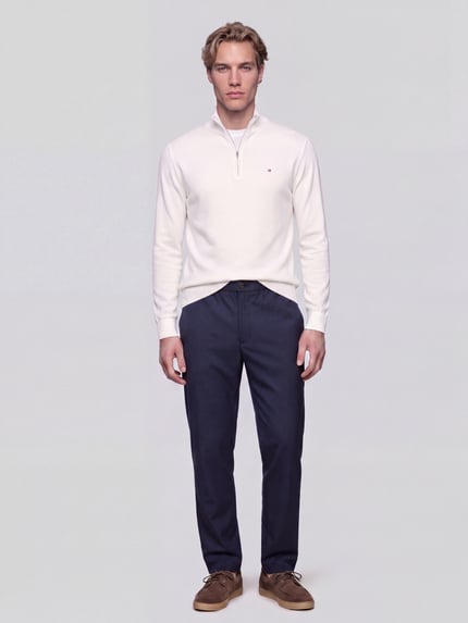 Männermodel trägt Low Waist Stoffhose mit Logo-Detail von Tommy Hilfiger in Dunkelblau, feines Web-Design, Gerade Passform, Ganzkörperansicht von vorne.