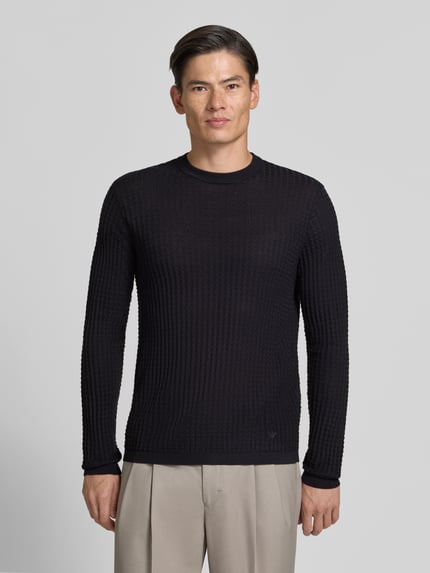Männermodel trägt Strickpullover mit Struktur-Muster von Emporio Armani in Schwarz, Rundhalsausschnitt, Material-Mix mit Woll-Anteil, taillierter Schnitt, Ganzkörperansicht von vorne.