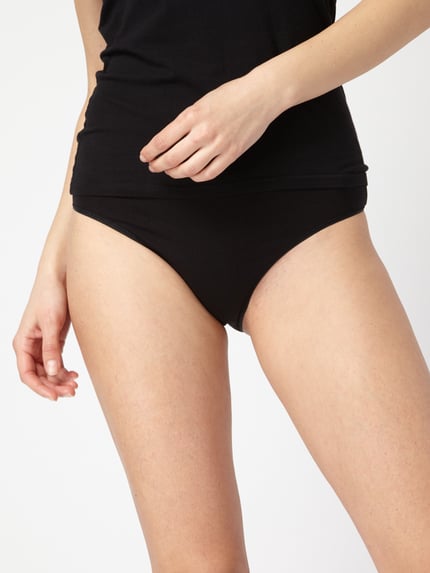 Kobiece model prezentuje figi Slip im 3er-Pack od Schiesser, czarny kolor, mieszanka bawełny i elastanu, dopasowany krój, elastyczny pas, zestaw 3 szt., zbliżenie na biodra.