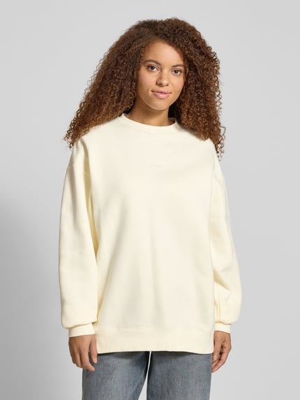 Frauenmodel trägt cremefarbenes Sweatshirt mit Rundhalsausschnitt Modell 'Good Karma' von OH APRIL, Oversized, Ganzkörperansicht von vorne.