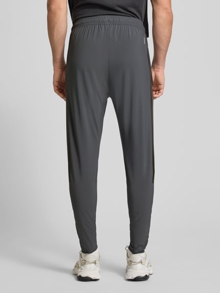 Męski model nosi Regular Fit Jogpants z elastycznym pasem model 'TIRO' od adidas Sportswear, szara tkanina, widok całej sylwetki od tyłu.