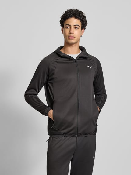 Männermodel trägt schwarze Regular Fit Trainingsjacke mit Logo-Print von PUMA PERFORMANCE, Kapuze, Reißverschluss, Eingrifftaschen, elastische Abschlüsse, Ganzkörperansicht von vorne.