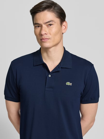 Männermodel trägt Regular Fit Poloshirt aus Baumwoll-Mix von Lacoste, unifarben navy, Logo-Detail, Piqué-Textur, Nahaufnahme Oberkörper.