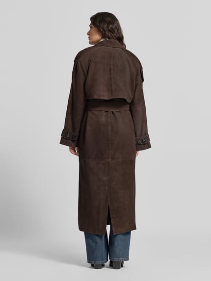 Frauenmodel trägt Mantel aus Lammvelours mit Bindegürtel von Cph Muse in Dunkelbraun, strukturierte Optik, lange Form, Label-Detail, Ganzkörperansicht Rückansicht.