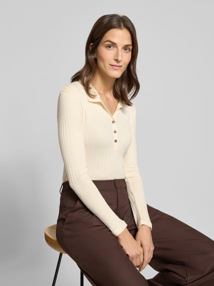 Vrouwenmodel draagt Slim Fit Langarmshirt aus Baumwoll-Modal-Mix van Marc O'Polo in effen crème, ribstructuur, Henley-hals, lange mouw, close-up bovenlichaam.