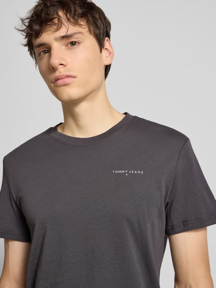 Männermodel trägt Regular Fit T-Shirt aus reiner Baumwolle von Tommy Jeans, unifarben, Label Print, Rundhals, kurzarm, Nahaufnahme Oberkörper.