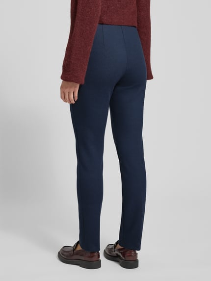 Kobiece model prezentuje granatowe spodnie Stoffhose mit französischen Eingrifftaschen Modell 'Lillyth' od Raphaela By Brax, materiał z dodatkiem wiskozy, prosty krój, widok całej sylwetki od tyłu.