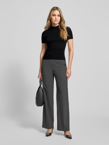 Frauenmodel trägt Slim Fit T-Shirt aus Viskose-Mix Modell 'SINANT' von HUGO in Schwarz mit Strukturmuster, unifarben, Kurzarm, hochgeschlossen, Ganzkörperansicht von vorne.