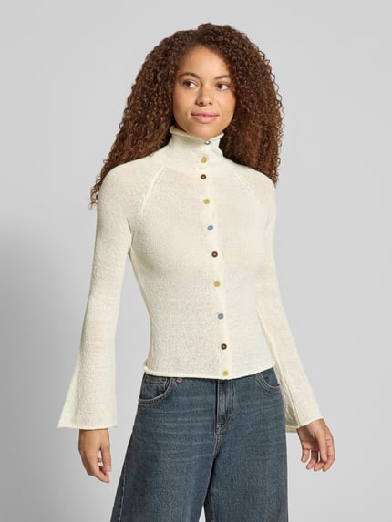 Frauenmodel trägt Slim Fit Cardigan mit Rollsaum Modell 'FOLKLORE' von DAISY STREET in Creme mit Knopfleiste, leicht melierte Textur, Nahaufnahme Oberkörper.
