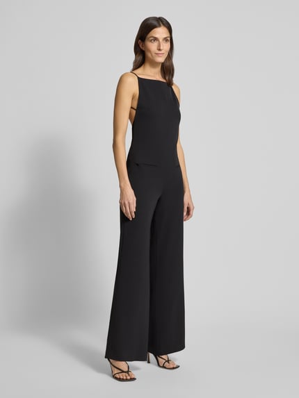 Frauenmodel trägt Jumpsuit mit Eingrifftaschen von Mango in Schwarz, lockerer Schnitt, Spaghettiträger, Square-Neck-Ausschnitt, Material-Mix mit Stretch-Anteil, Ganzkörperansicht von vorne.