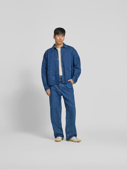 Männermodel trägt Straight Fit Jeans mit Logo-Detail von WON HUNDRED aus Reine Baumwolle in Blau, Ganzkörperansicht von vorne. Innenbeinlänge 78 cm, Bundweite 45 cm, Eingriff- und Gesäßtaschen, Knopf- und Reißverschluss.