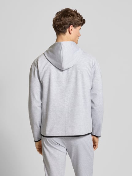 Männermodel trägt Regular Fit Sweatjacke mit Kapuze Modell 'Base' von Jack & Jones in hellgrau, glatte Struktur, Ganzkörperansicht Rückansicht, elastischer Baumwoll-Mix, Reißverschluss und Taschen sichtbar.