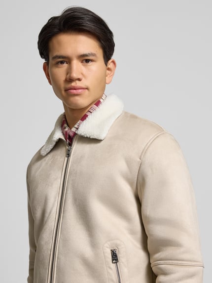 Männermodel trägt Regular Fit Bomberjacke mit Kunstfellkragen Modell 'ROYCE' von Only & Sons in Wildleder-Optik, Nahaufnahme Oberkörper.
