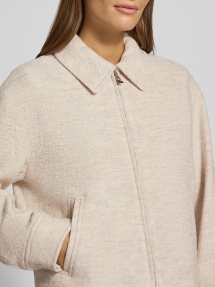 Vrouwenmodel draagt Regular Fit Blazer aus Viskose-Woll-Mix mit Eingrifftaschen van comma, lichtbeige, zachte textuur, Nahaufnahme Oberkörper. Ruglengte maat 36: 44 cm, borstwijdte maat 36: 54 cm, mouwlengte maat 36: 55 cm.