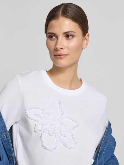 Frauenmodel trägt Regular Fit T-Shirt mit Rüschenbesatz von Comma, Reine Baumwolle, Rundhalsausschnitt, Weiß, Nahaufnahme Oberkörper.