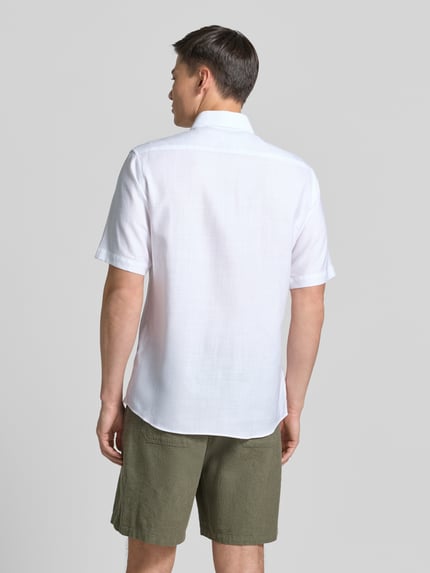 Männermodel trägt Modern Fit Business-Hemd mit Kentkragen von ETERNA aus Baumwoll-Lyocell-Mix, 1/2-Arm, weiße Farbe, Ganzkörperansicht Rückansicht.