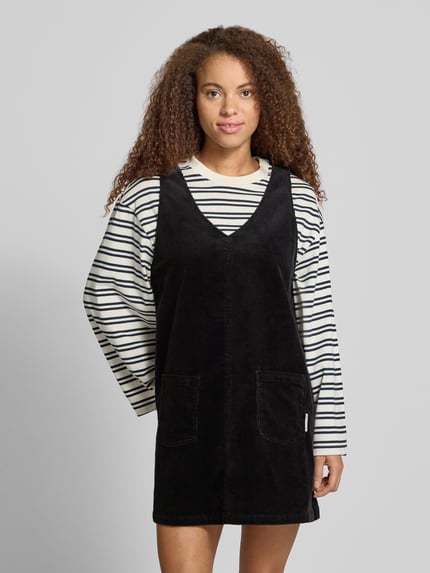 Frauenmodel trägt Minikleid aus Baumwoll-Mix von Marc O'Polo DENIM in Schwarz, unifarben mit V-Ausschnitt und aufgesetzten Taschen, Cordstruktur, Ganzkörperansicht von vorne.