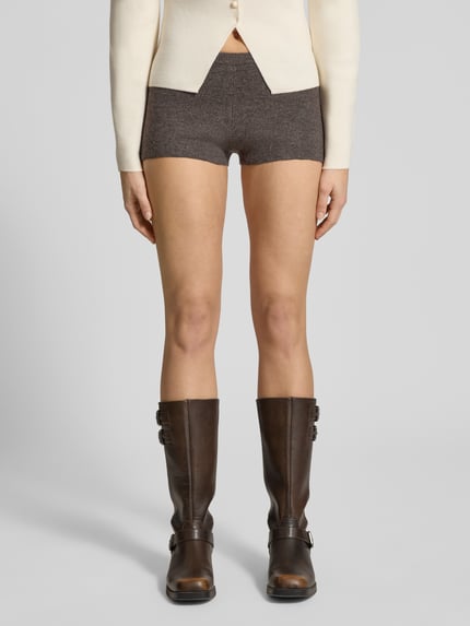 Kobiece modelka nosi Slim Fit Shorts mit Woll-Anteil in Strick-Optik von Gina Tricot, mieszanka materiałów z dodatkiem wełny, krój slim fit, imitacja dzianiny, elastyczny pas, szerokość w rozmiarze S: 31 cm, długość wewnętrzna nogawki w rozmiarze S: 3 cm, odcień brązu, gładka tekstura, całkowity widok z przodu.