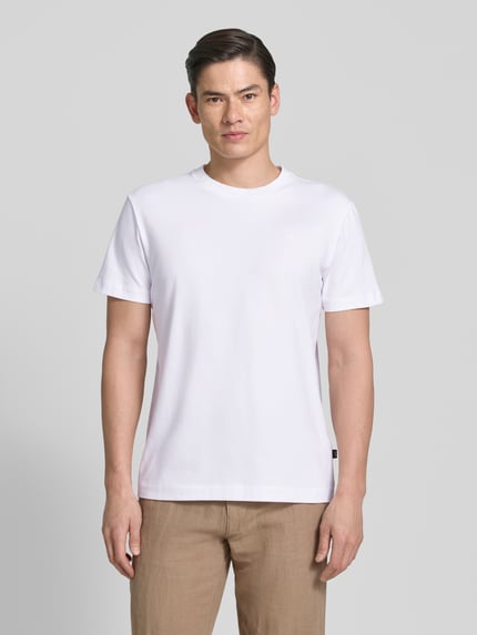 Männermodel trägt T-Shirt mit Rundhalsausschnitt Modell 'Carlonito' von JOOP! Collection in Weiß, Baumwoll-Mix, Straight Fit, Ganzkörperansicht von vorne.