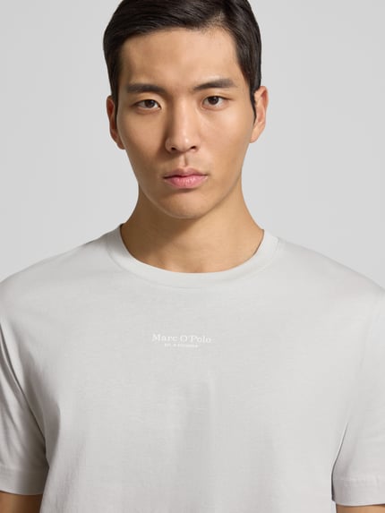 Męski model nosi Regular Fit T-Shirt aus reiner Baumwolle od Marc O'Polo, jednolity kolor, krótki rękaw, bawełna, nadruk z logo, jersey. Zbliżenie na górną część ciała.