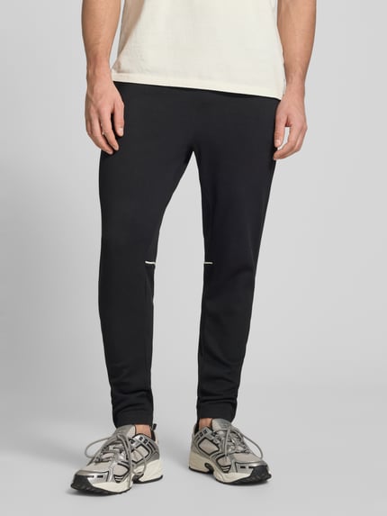 Männermodel trägt czarny Slim Fit Tracksuit mit Logo-Stitching Modell 'Egeo' von SERGIO TACCHINI, elastyczna mieszanka bawełny, krój slim fit, zakończenia elastyczne, widoczny stebnowany logotyp, przód, zbliżenie na dolną część ciała