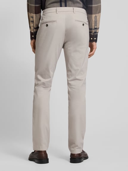 Mannenmodel draagt Regular Fit Chino uit katoenmix model 'DENTON' van Tommy Hilfiger met all-over motief, riemlussen, steek- en achterzakken, knoop- en ritssluiting, kleur lichtbeige, look: regular fit, materiaal: katoenmix, geheel achteraanzicht.