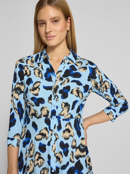 Frauenmodel trägt Hemdblusenkleid aus Viskose Modell 'SAVANNA' von YAS mit blau-schwarz-beigem Muster, Knopfleiste, Kentkragen, Nahaufnahme Oberkörper.