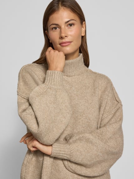 Frauenmodel trägt Strickkleid mit Stehkragen und überschnittenen Schultern von Apricot, Woll-Materialmix, gerade Form, Nahaufnahme Oberkörper.