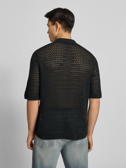 Männermodel trägt Regular Fit Poloshirt aus Baumwoll-Mix Modell 'NYLE' von Only & Sons, schwarze Strickstruktur, Ganzkörperansicht Rückansicht.