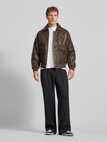 Männermodel trägt Regular Fit Jacke in Leder-Optik Modell 'MORANO' von PEGADOR in Braun, glatte Struktur, Ganzkörperansicht von vorne. Rückenlänge 66 cm, Schulterbreite 44 cm, Brustweite 59 cm, Ärmellänge 71 cm.