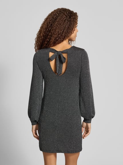 Frauenmodel trägt Langarmshirt mit Glitzerstruktur von ONLY in dunklem Unifarbton mit Strukturmuster, leicht glänzende Jersey-Optik, geschlitzter Saum, elastische lange Ärmel, hoher Ausschnitt, Ganzkörperansicht Rückansicht.