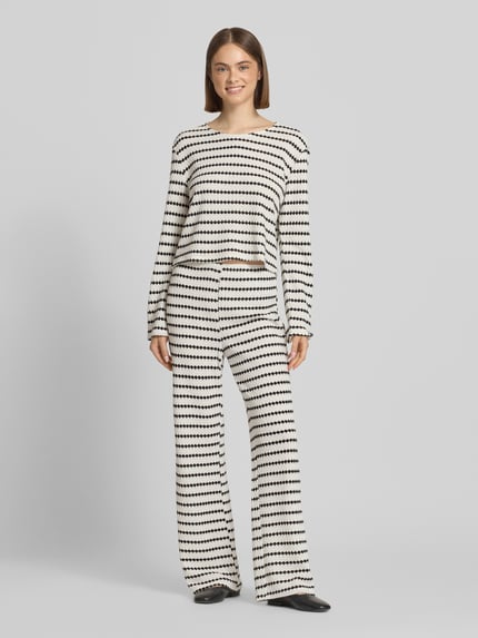 Frauenmodel trägt Relaxed Fit Langarmshirt mit Baumwoll-Anteil Modell 'EVA' von Only, Optik:Allover-Muster, Struktur, Cropped, Rundhals, langarm, Feinstrick, in Schwarz-Weiß-Tönen; Ganzkörperansicht von vorne.