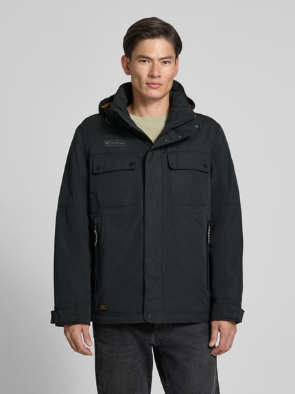 Männermodel trägt zwarte tussenjack met capuchon, statementpatch en rits- plus drukknoopsluiting, Jacke mit Kapuze Modell 'Between Funktion TEXX' van camel active, recht model, vooraanzicht, Nahaufnahme Oberkörper.