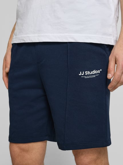 Männermodel trägt Sweatshorts mit Logo Model 'KANE' von Jack & Jones aus Baumwoll-Mix, Relaxed-Fit, Dunkelblau, Nahaufnahme Oberkörper.