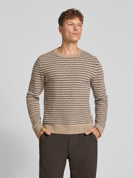 Männermodel trägt Pullover aus Wolle mit Strukturstrick von GANT, mehrfarbiges Allover-Muster, Strickoptik, Ganzkörperansicht von vorne.